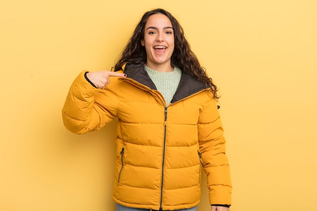 Mulher bonita hispânica parecendo feliz, orgulhosa e surpresa apontando alegremente para se sentir confiante e elevada