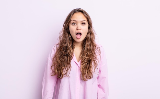 Mulher bonita hispânica parecendo muito chocada ou surpresa, olhando com a boca aberta dizendo uau