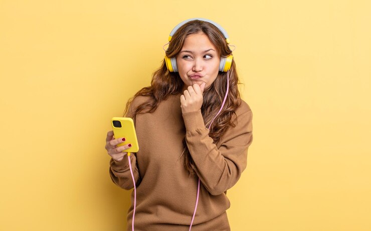 Foto mulher bonita hispânica pensando, sentindo-se duvidosa e confusa. conceito de fones de ouvido e smartphone