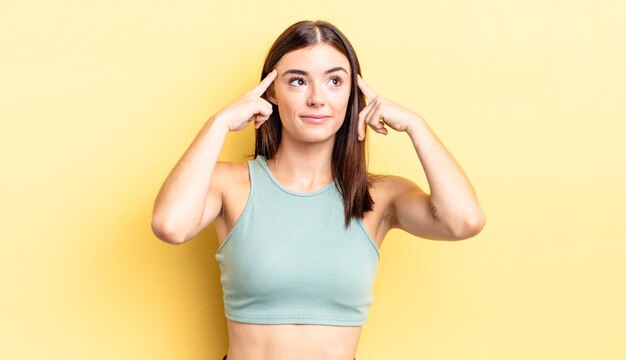 Mulher bonita hispânica se sentindo confusa ou em dúvida, concentrada em uma ideia, pensando muito, procurando copiar o espaço ao lado