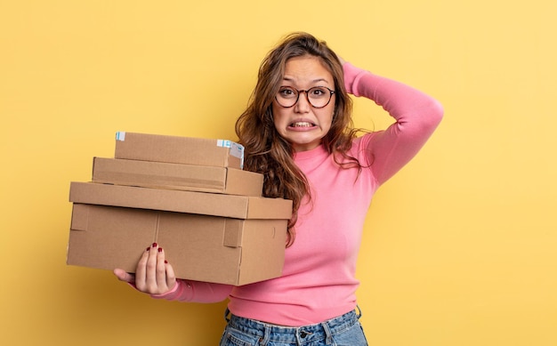 Mulher bonita hispânica se sentindo estressada, ansiosa ou assustada com as mãos no conceito de armazenamento de cabeça