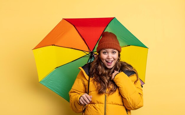 Mulher bonita hispânica se sentindo feliz e apontando para si mesmo com um conceito de guarda-chuva animado