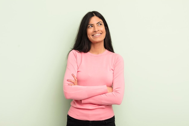 Mulher bonita hispânica se sentindo feliz, orgulhosa e esperançosa pensando ou pensando olhando para copiar o espaço com os braços cruzados