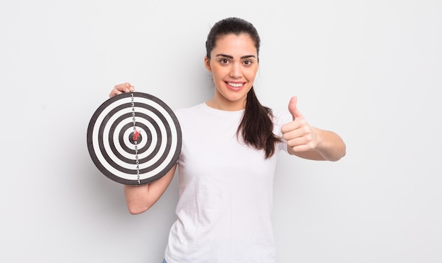 mulher bonita hispânica se sentindo orgulhosa, sorrindo positivamente com polegares para cima. conceito de alvo de dardos