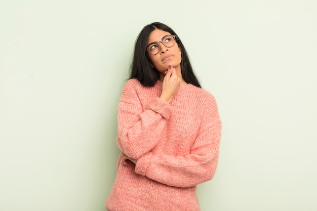 Mulher bonita hispânica se sentindo pensativa pensando ou imaginando ideias sonhando acordada e olhando para cima para copiar o espaço