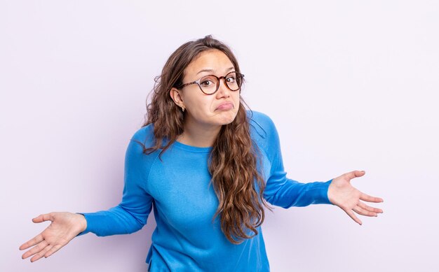 Mulher bonita hispânica se sentindo sem noção e confusa, sem fazer ideia, absolutamente perplexa com uma aparência idiota ou tola