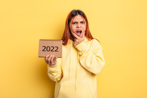 mulher bonita hispânica segurando um calendário ou agenda 2022