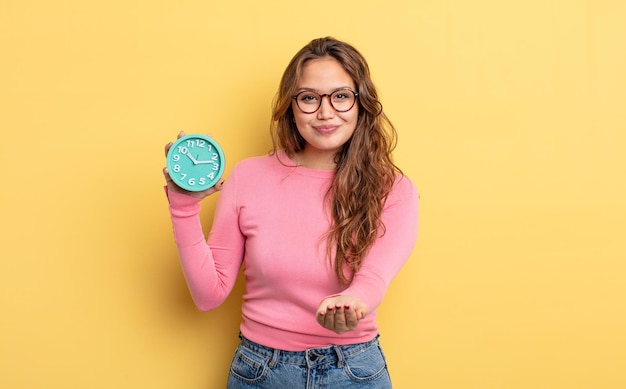 Mulher bonita hispânica sorrindo alegremente com amigável e oferecendo e mostrando um conceito. conceito de despertador