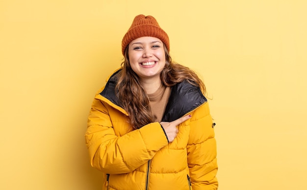 Mulher bonita hispânica sorrindo alegremente se sentindo feliz e apontando para o lado roupas de inverno