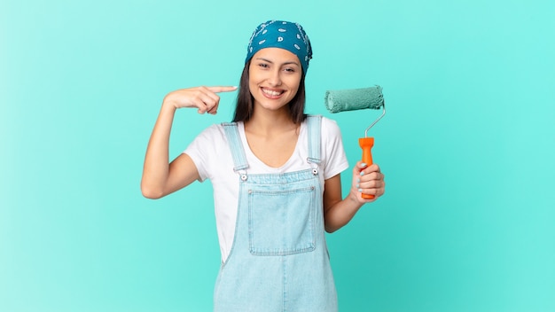 Mulher bonita hispânica sorrindo com confiança, apontando para o próprio sorriso largo. conceito de pintura de casa