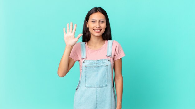 Mulher bonita hispânica sorrindo e parecendo amigável, mostrando o número cinco