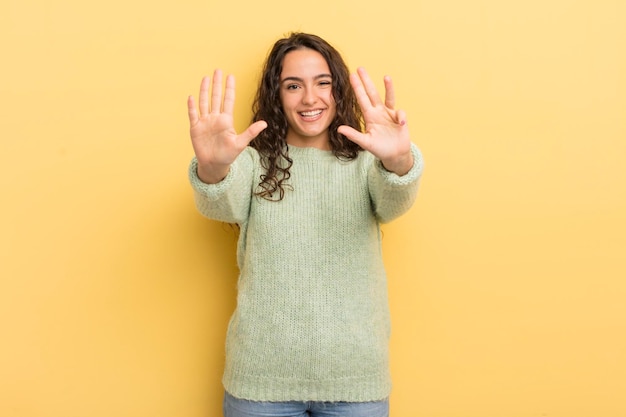 Mulher bonita hispânica sorrindo e parecendo amigável mostrando o número nove ou nono com a mão em contagem regressiva