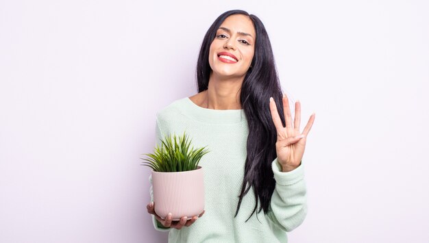 Mulher bonita hispânica sorrindo e parecendo amigável, mostrando o número quatro. conceito de planta de casa