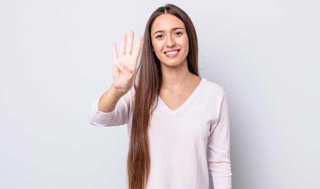 Mulher bonita hispânica sorrindo e parecendo amigável mostrando o número quatro ou quarto com a mão em contagem regressiva