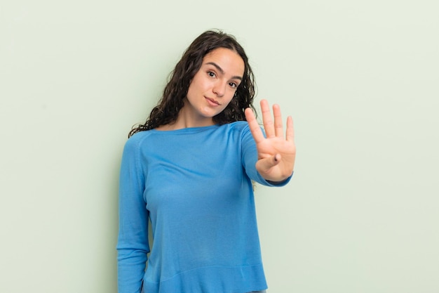 Mulher bonita hispânica sorrindo e parecendo amigável mostrando o número quatro ou quarto com a mão em contagem regressiva