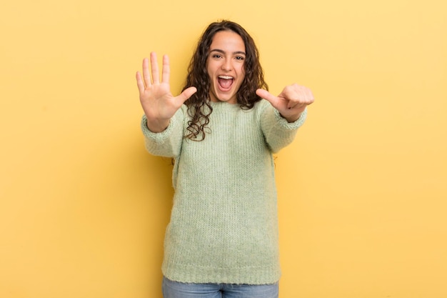 Mulher bonita hispânica sorrindo e parecendo amigável, mostrando o número seis ou sexto com a mão para a frente, em contagem regressiva