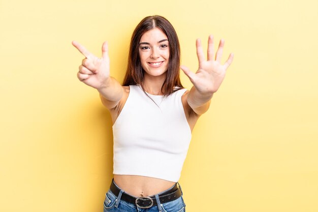 Mulher bonita hispânica sorrindo e parecendo amigável mostrando o número sete ou sétimo com a mão em contagem regressiva