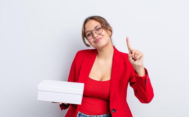 Mulher bonita hispânica sorrindo e parecendo amigável, mostrando o número um. conceito de produto de embalagem