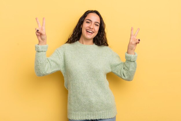 Mulher bonita hispânica sorrindo e parecendo feliz amigável e satisfeita gesticulando vitória ou paz com as duas mãos