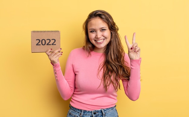 Mulher bonita hispânica sorrindo e parecendo feliz, gesticulando vitória ou paz. conceito de calendário