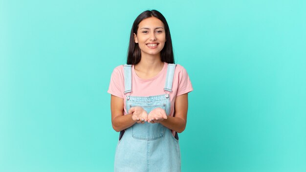 Mulher bonita hispânica sorrindo feliz com simpatia e oferecendo e mostrando um conceito