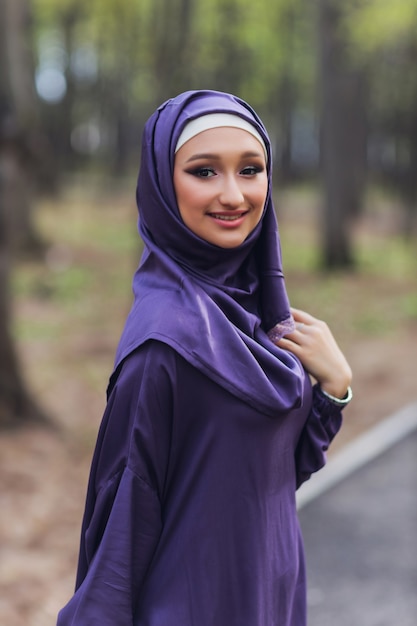 Mulher bonita islâmica em um vestido muçulmano de pé em um parque de verão rua fundo floresta outono trees.world hijab dia.