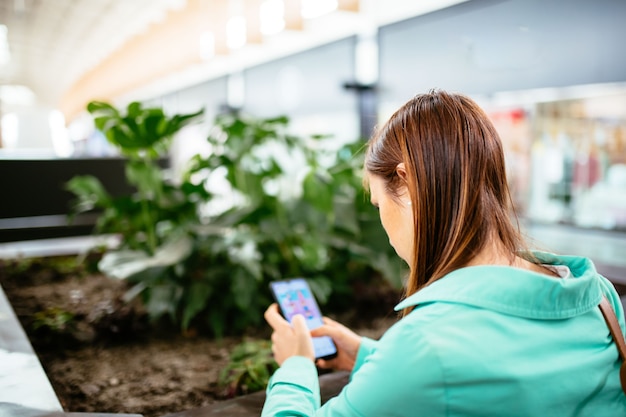 Mulher bonita jovem de meia-idade por trás, olhando para a tela do smartphone. mulher de negócios.adição às telas