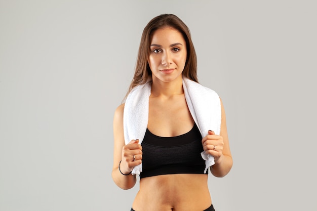 Mulher bonita jovem esportes posando com toalha no pescoço