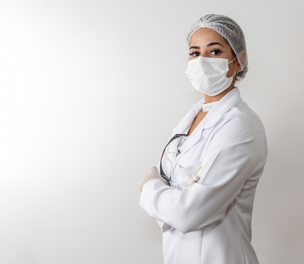 Mulher bonita jovem médico no jaleco branco e uma máscara protetora e luvas de borracha.