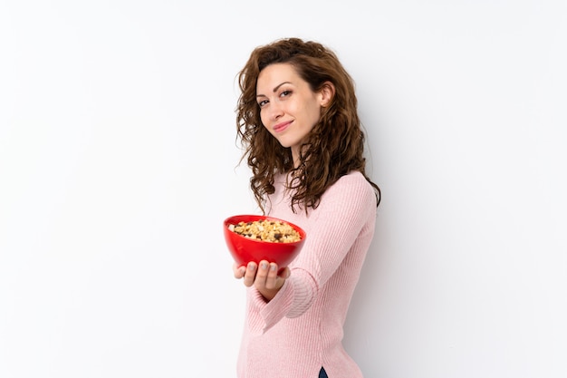 Foto mulher bonita jovem sobre parede isolada, segurando uma tigela de cereais