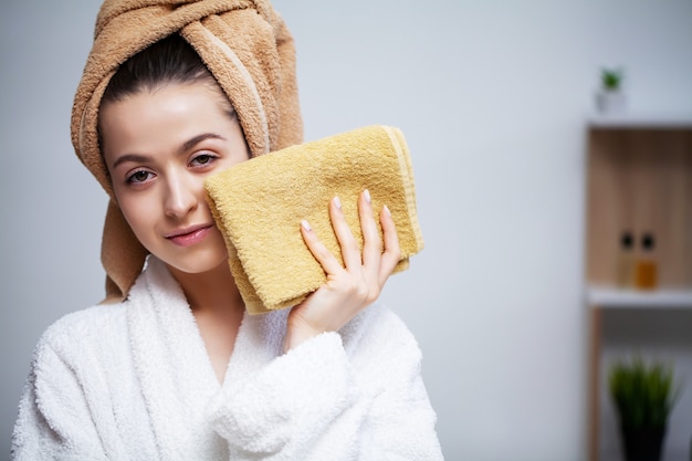 Mulher bonita limpa a toalha de rosto depois de tomar banho