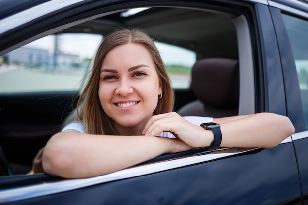 Mulher bonita loira elegante sentada em um carro de luxo. A menina é estilosa e ganha muito. conceito de empresário mulher independente