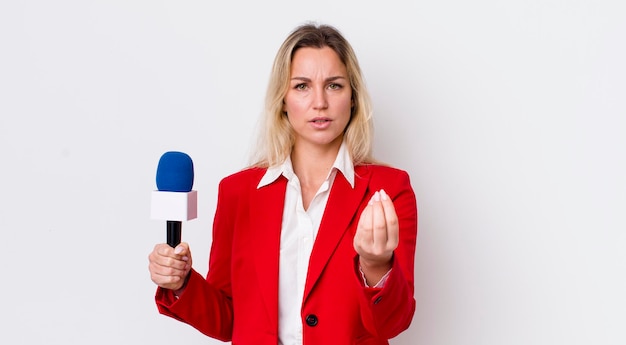 Mulher bonita loira fazendo gesto de capice ou dinheiro dizendo para você pagar o conceito de preporter e microfone