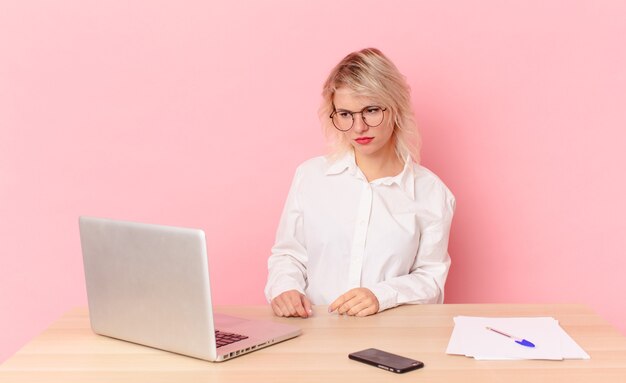 Mulher bonita loira jovem bonita se sentindo triste, chateada ou com raiva e olhando para o lado. conceito de mesa de trabalho