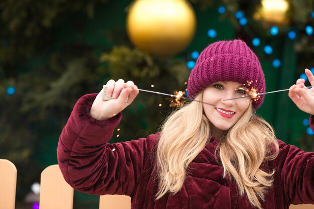 Mulher bonita loira se divertindo com luzes cintilantes de bengala no abeto de ano novo em Kiev