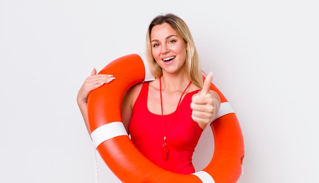 Mulher bonita loira se sentindo orgulhosa sorrindo positivamente com polegares para cima conceito de salva-vidas