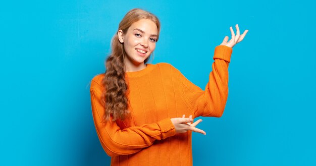 Mulher bonita loira sorrindo com orgulho e confiança, sentindo-se feliz e satisfeita e mostrando um conceito no espaço da cópia