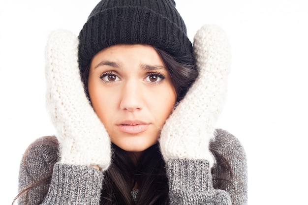 Mulher bonita morena com um chapéu de lã uma camisola e luvas que tem frio