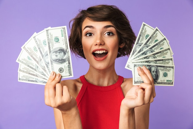 Mulher bonita morena feliz mostrando dinheiro enquanto olha para a câmera