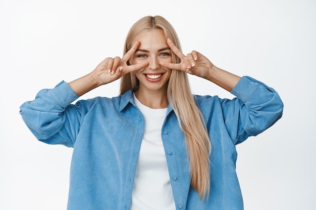 Mulher bonita mostra paz, gesto de dedos de discoteca e sorrindo feliz, conceito de positividade e estilo de vida, de pé em branco.