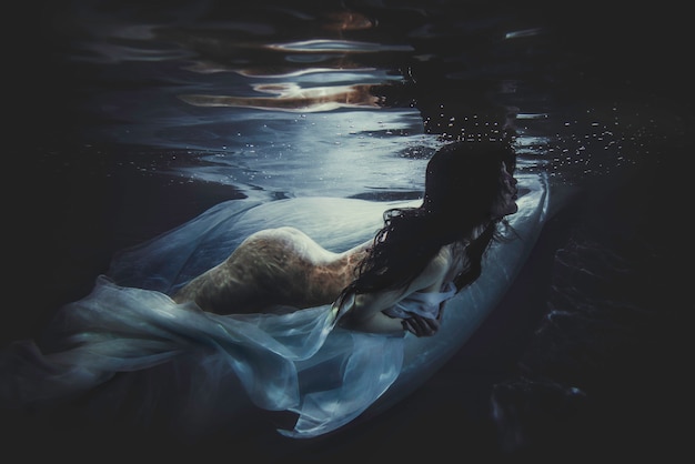 Mulher bonita nadando com vestido extravagante debaixo d'água