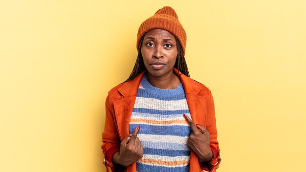 Mulher bonita negra afro apontando para si mesma com um olhar confuso e curioso, chocada e surpresa por ser escolhida