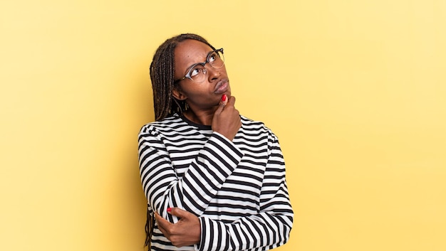 Mulher bonita negra afro pensando se sentindo duvidosa e confusa com diferentes opções imaginando qual decisão tomar