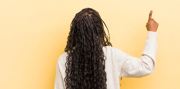 Mulher bonita negra em pé e apontando para o objeto na vista traseira do espaço de cópia