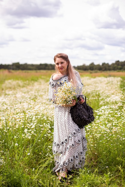 Mulher bonita no campo com flores. Foto de alta qualidade