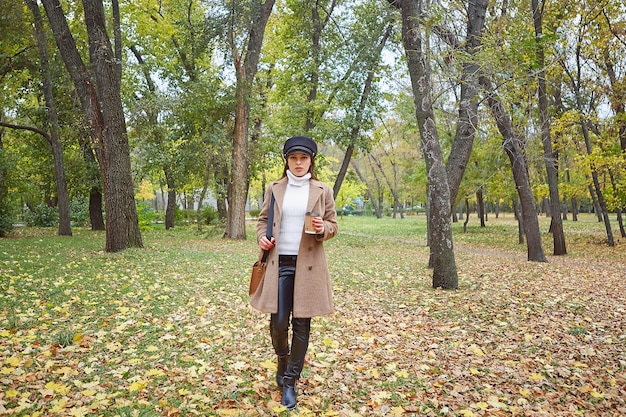 Mulher bonita no parque outono com café