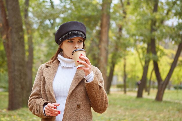 Mulher bonita no parque outono com café