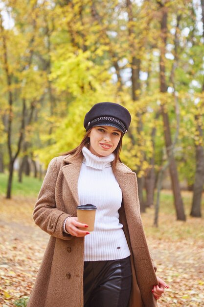 Mulher bonita no parque outono com café