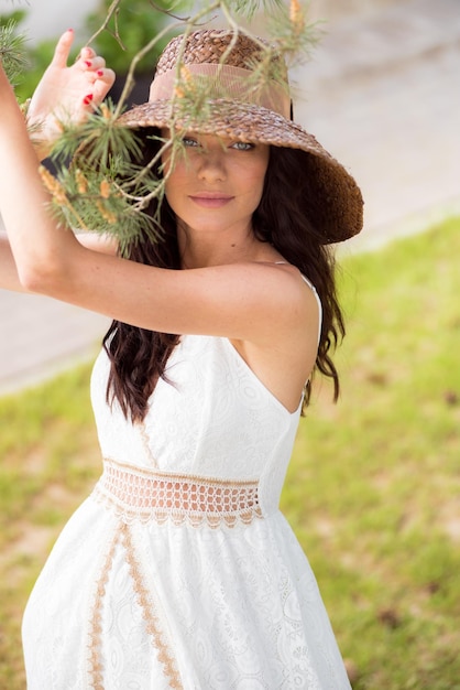 Mulher bonita no vestido branco de verão e chapéu de palha