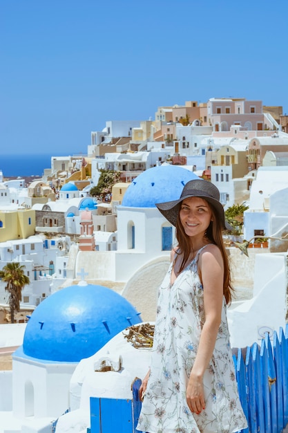 Mulher bonita no vestido branco no fundo da arquitetura em Santorini.